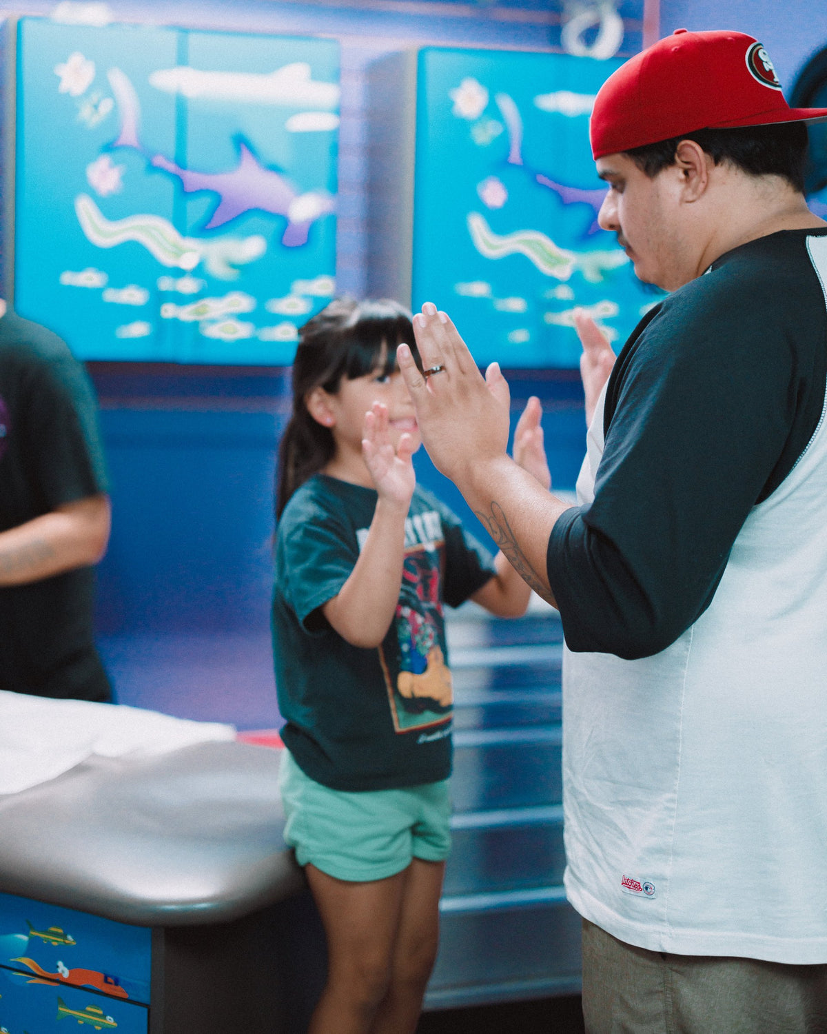 A young client high-fives her dad after her ear piercing