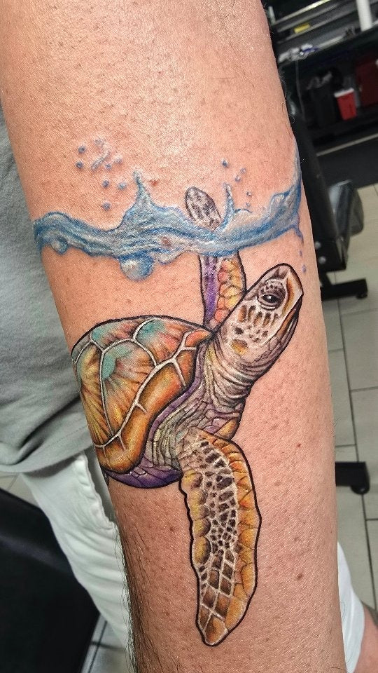 Tattoo by Angel at Z-Edge Gulf Gate: color sea turtle under a wave on the forearm