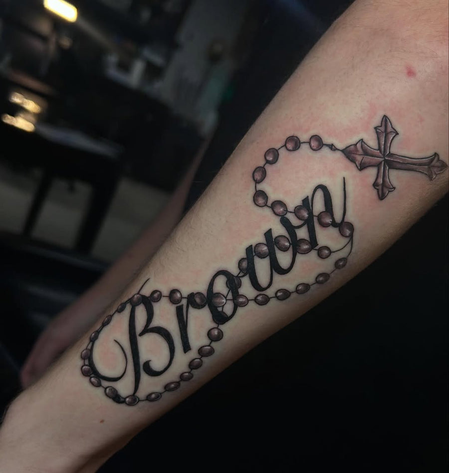 Tattoo by Manny at Z-Edge Gulf Gate: rosary cross script lettering forearm